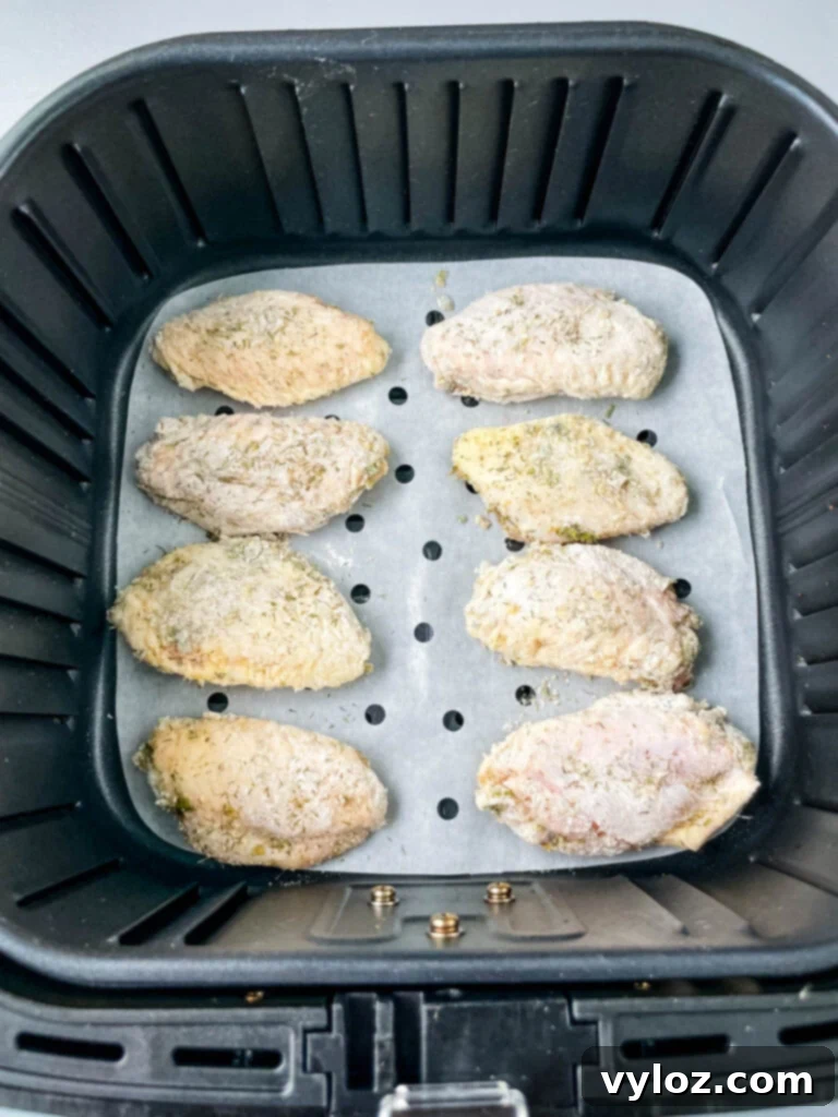 Raw ranch seasoned chicken wings arranged in an air fryer basket, ready for cooking.