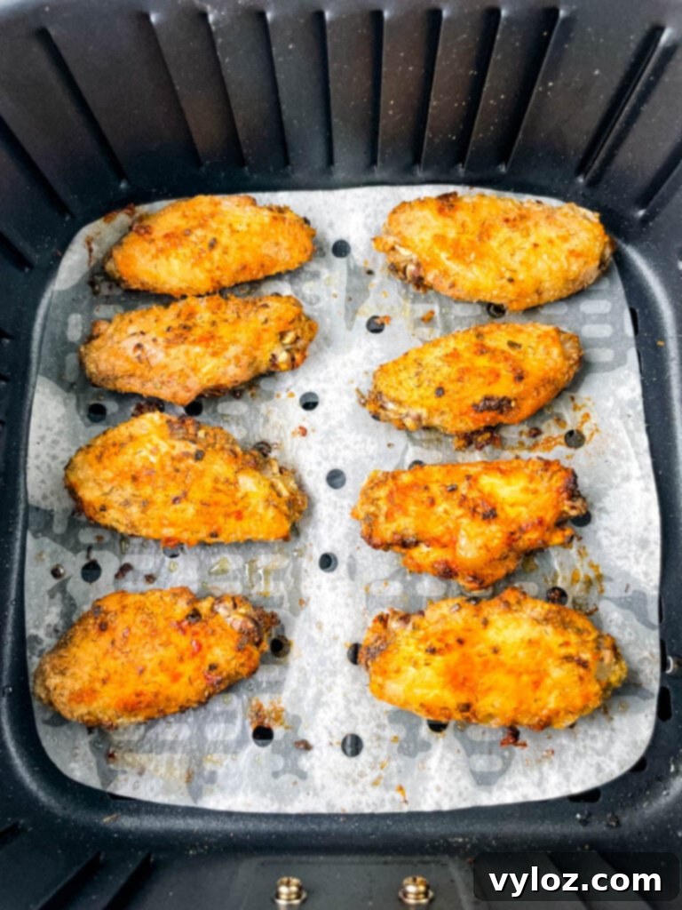A batch of golden-brown ranch chicken wings cooking inside an air fryer basket.