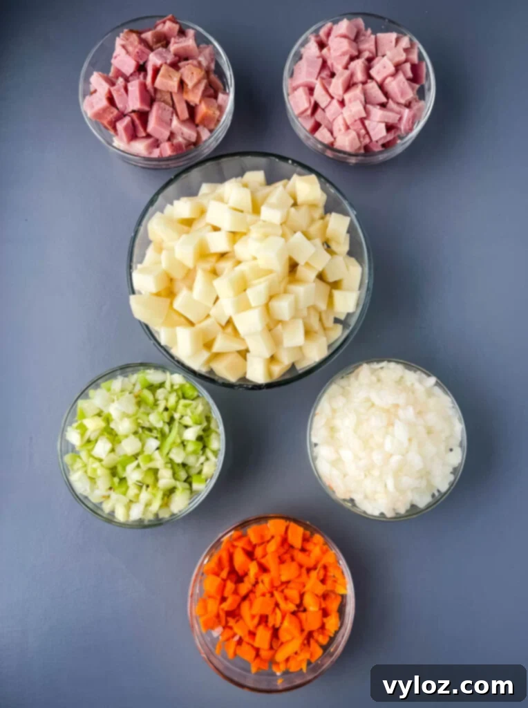 Separate glass bowls containing diced ham, diced potatoes, diced celery, diced carrots, and diced onions, showcasing prepared ingredients for the soup.
