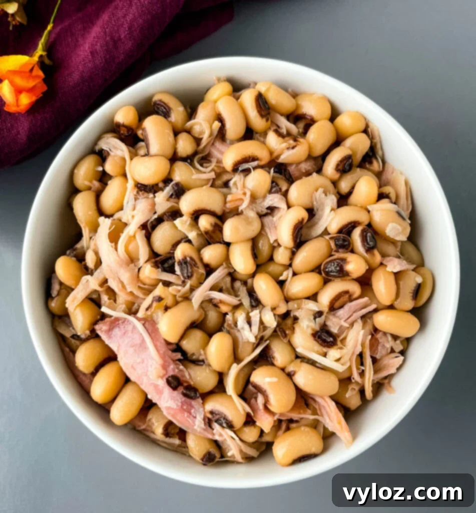 Classic Southern Black Eyed Peas and Smoked Turkey 9 A bowl of Southern black eyed peas with smoked turkey, presented on a rustic wooden surface, emphasizing comfort and homestyle cooking.