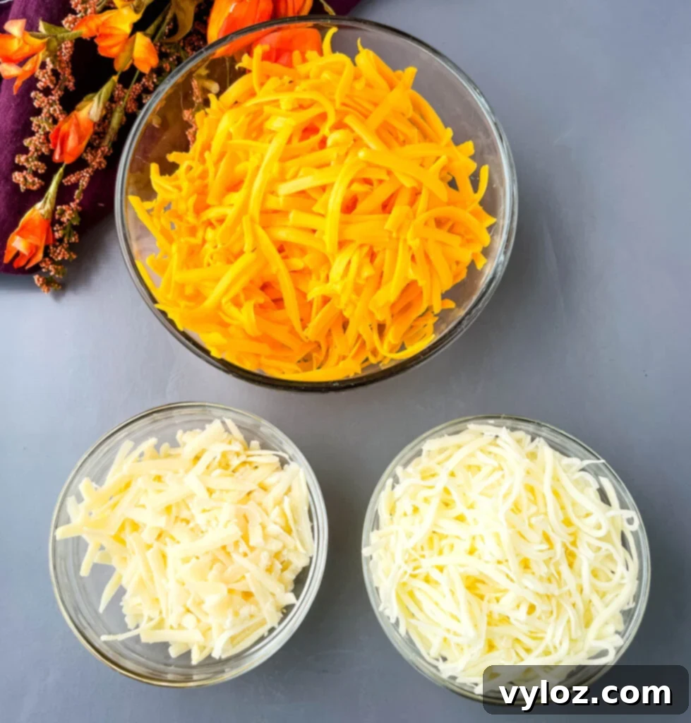 Gourmet Seafood Mac & Cheese 4 Glass bowls filled with freshly shredded sharp cheddar, mozzarella, and Parmesan cheeses, ready for the mac and cheese sauce.