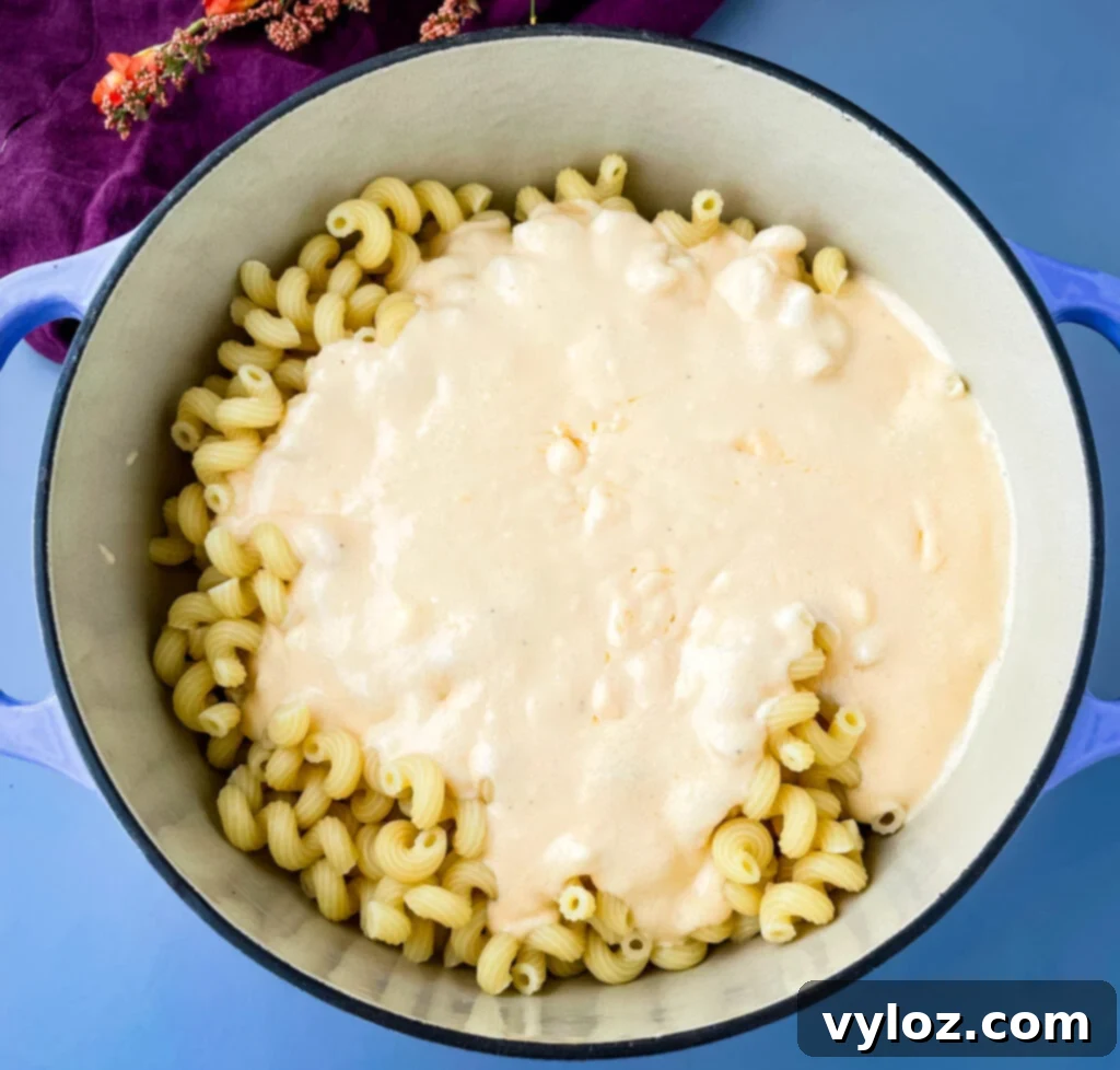 Gourmet Seafood Mac & Cheese 10 Cooked pasta mixed with creamy mac and cheese sauce in a Dutch oven, ready for the addition of seafood.