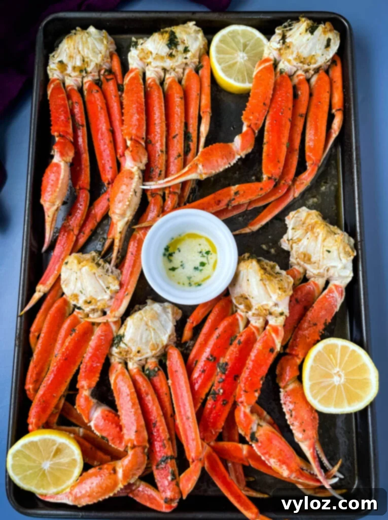 Decadent Garlic Butter Crab 2 baked crab legs on a pan with lemon garlic butter