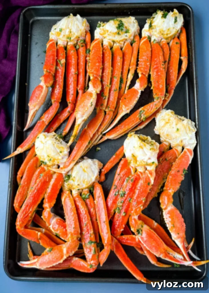 Decadent Garlic Butter Crab 5 baked crab legs on a pan with lemon garlic butter