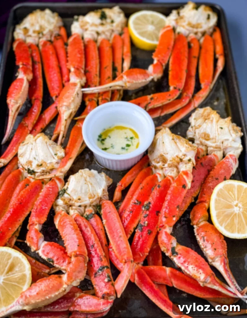 Decadent Garlic Butter Crab 6 baked crab legs on a pan with lemon garlic butter