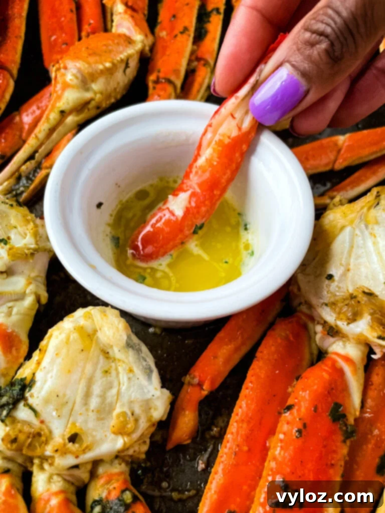Decadent Garlic Butter Crab 9 person holding crab leg meat dipped in butter