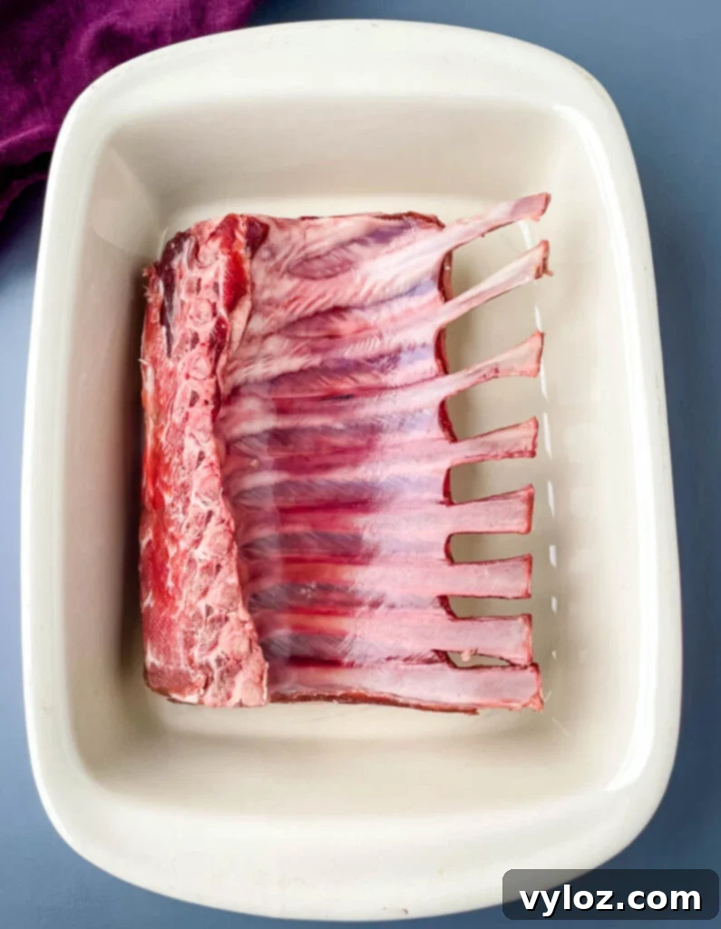 Raw rack of lamb in a baking dish, ready for seasoning.