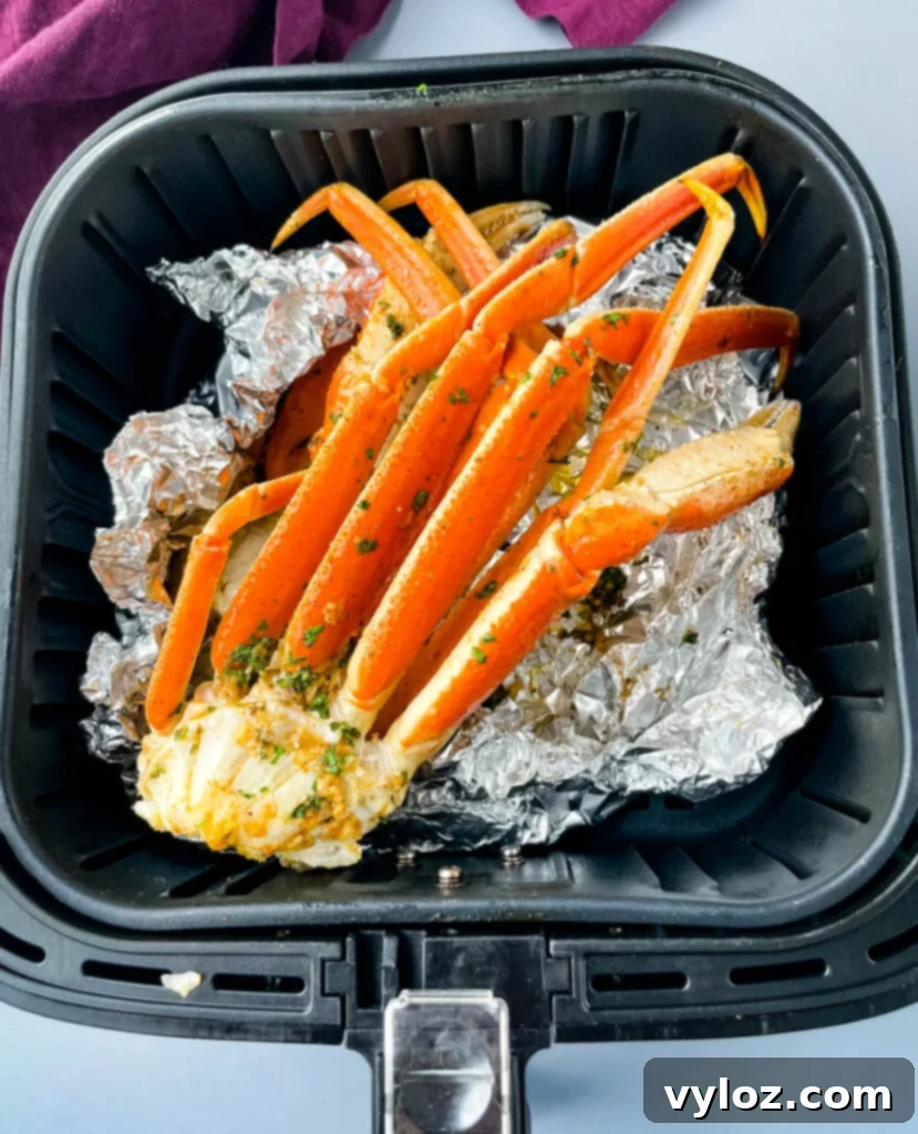 Easy Air Fryer Crab Legs 2 Perfectly cooked crab legs in an air fryer basket, wrapped in foil, ready to serve.