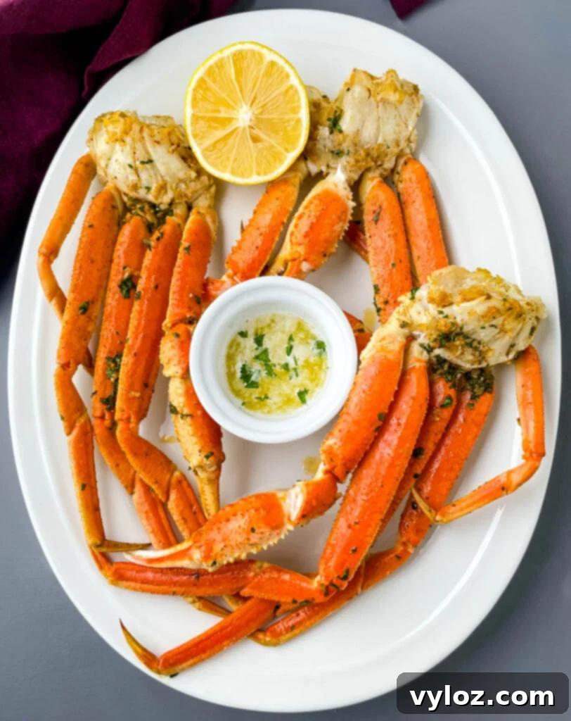 Easy Air Fryer Crab Legs 7 Air fried crab legs served on a white plate with a side of melted butter for dipping.