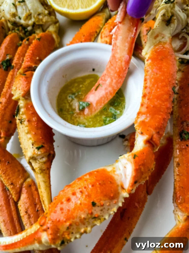 Easy Air Fryer Crab Legs 8 A person holding a piece of crab leg meat, dipped in a small bowl of melted butter, highlighting the tenderness and flavor.