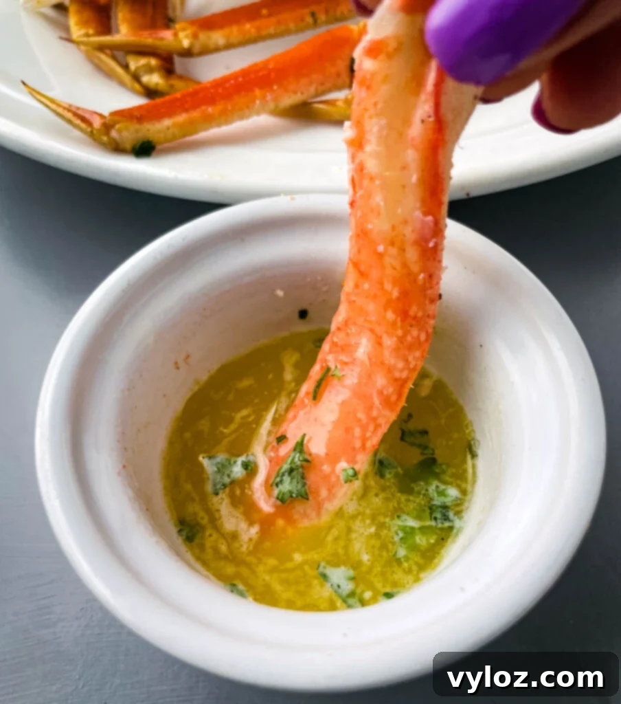 person holding crab leg meat dipped in butter