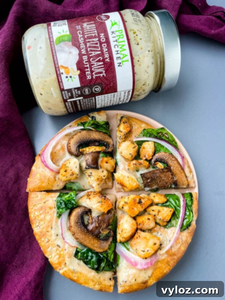 A perfectly cooked pita bread pizza, generously topped with chicken, spinach, mushrooms, and onions, cut into inviting slices, ready to be served.