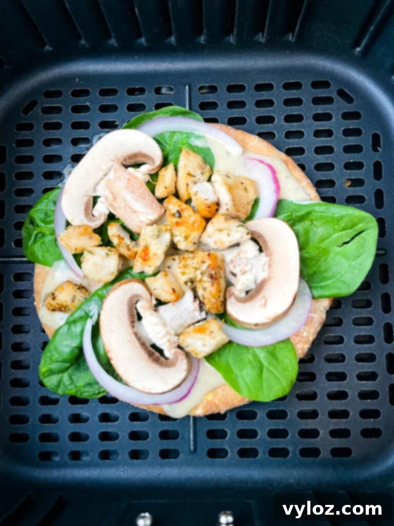 A golden-brown pita bread pizza cooking to perfection inside an air fryer basket, its toppings bubbling invitingly.