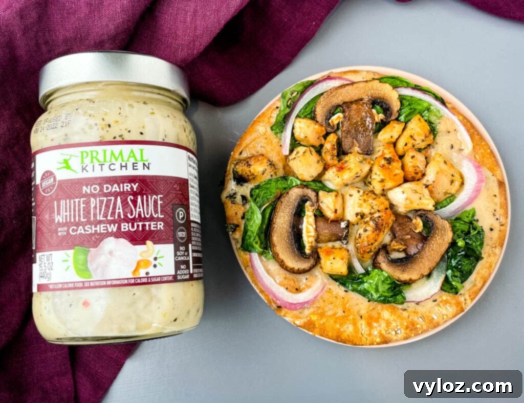 A close-up shot of a baked pita bread pizza, showcasing its generous topping of vibrant spinach, tender chicken, sliced mushrooms, and caramelized onions.