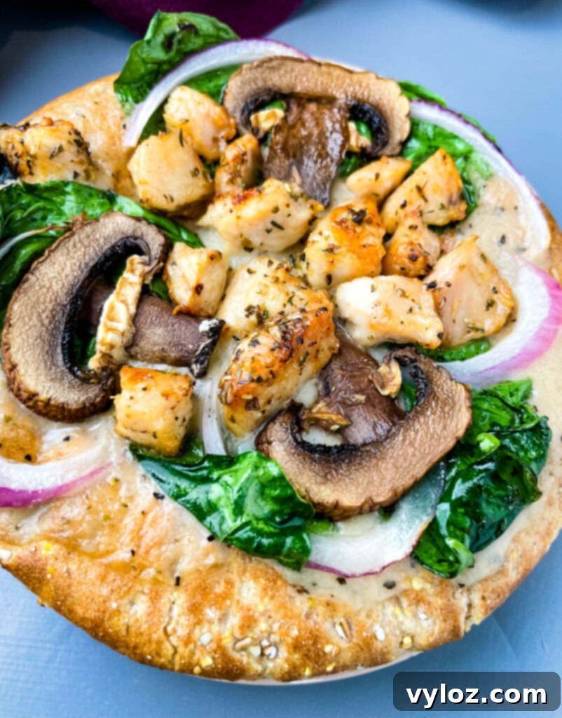 Another mouth-watering view of the pita bread pizza, showcasing the evenly distributed spinach, chicken, mushrooms, and onions, with a golden-brown, crispy crust.