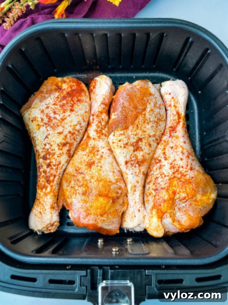 Seasoned raw turkey legs neatly arranged inside an air fryer basket, ready for cooking.