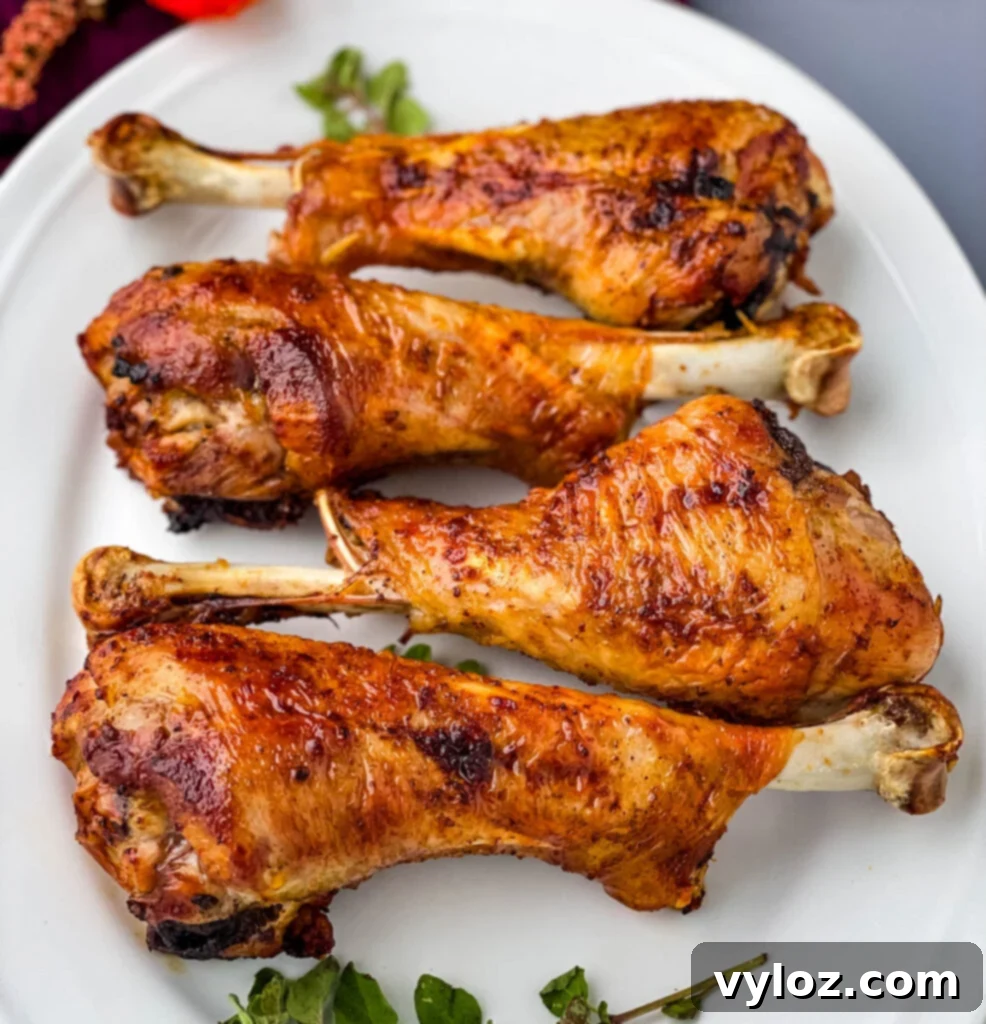 Close-up of a perfectly cooked air fryer turkey leg on a white plate, highlighting its crispy skin and juicy appearance.