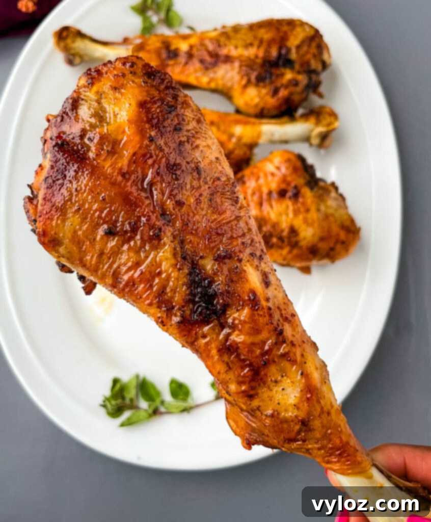 A person holding a perfectly cooked air fryer turkey leg, showing off its crispy skin and inviting appearance.