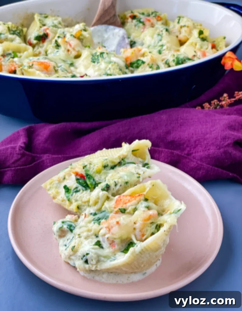 A single serving of seafood stuffed shells on a pink plate, garnished with fresh herbs, showcasing the creamy filling and melted cheese.