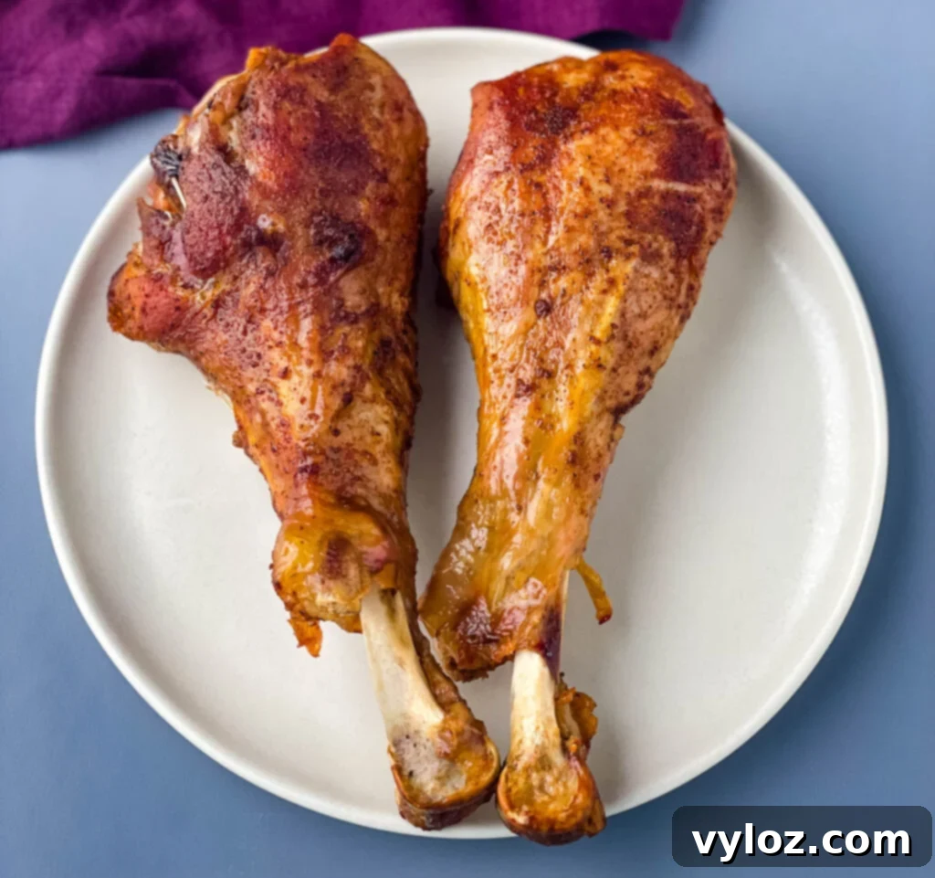 Two perfectly cooked slow cooker turkey legs on a plate, ready to be served