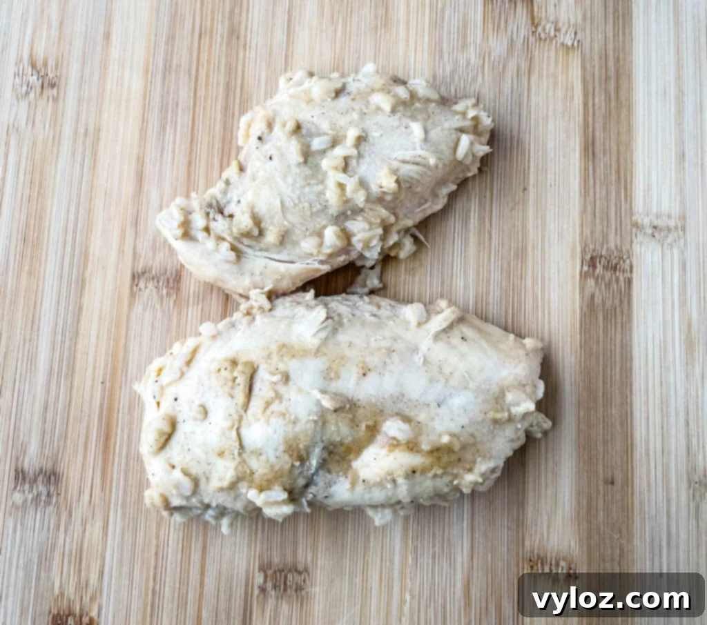 Creamy Cheesy Slow Cooker Chicken and Rice 7 Cooked chicken breasts resting on a cutting board, ready for shredding or cubing