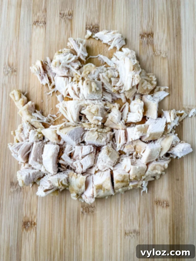 Creamy Cheesy Slow Cooker Chicken and Rice 8 Sliced and cubed cooked chicken breast on a cutting board, prepared for the slow cooker