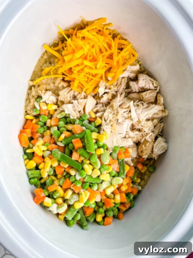 Creamy Cheesy Slow Cooker Chicken and Rice 9 Cooked chicken, rice, and mixed vegetables in a slow cooker Crockpot, ready to be served