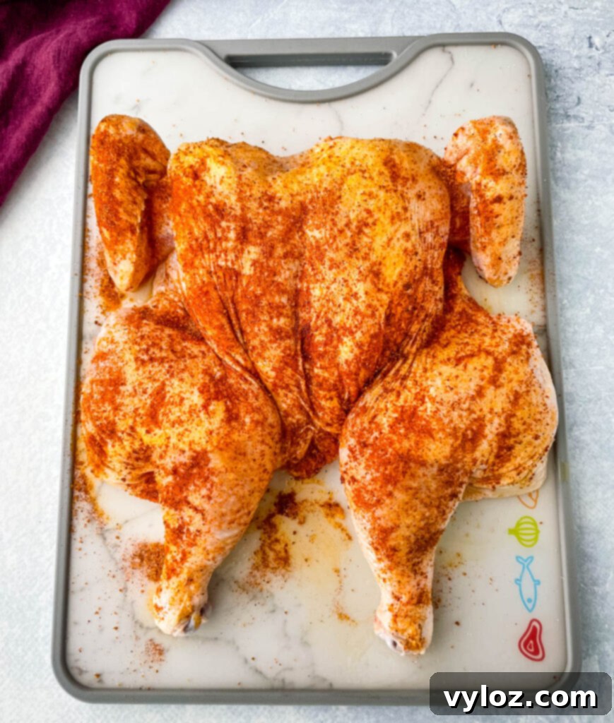 raw seasoned spatchcock chicken on a cutting board