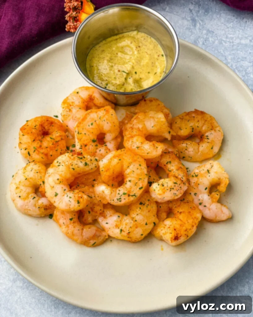 Crispy Air Fryer Frozen Shrimp 2 Cooked air fryer frozen shrimp on a plate with sauce