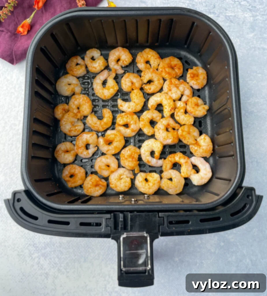 Crispy Air Fryer Frozen Shrimp 5 Frozen shrimp in air fryer being seasoned