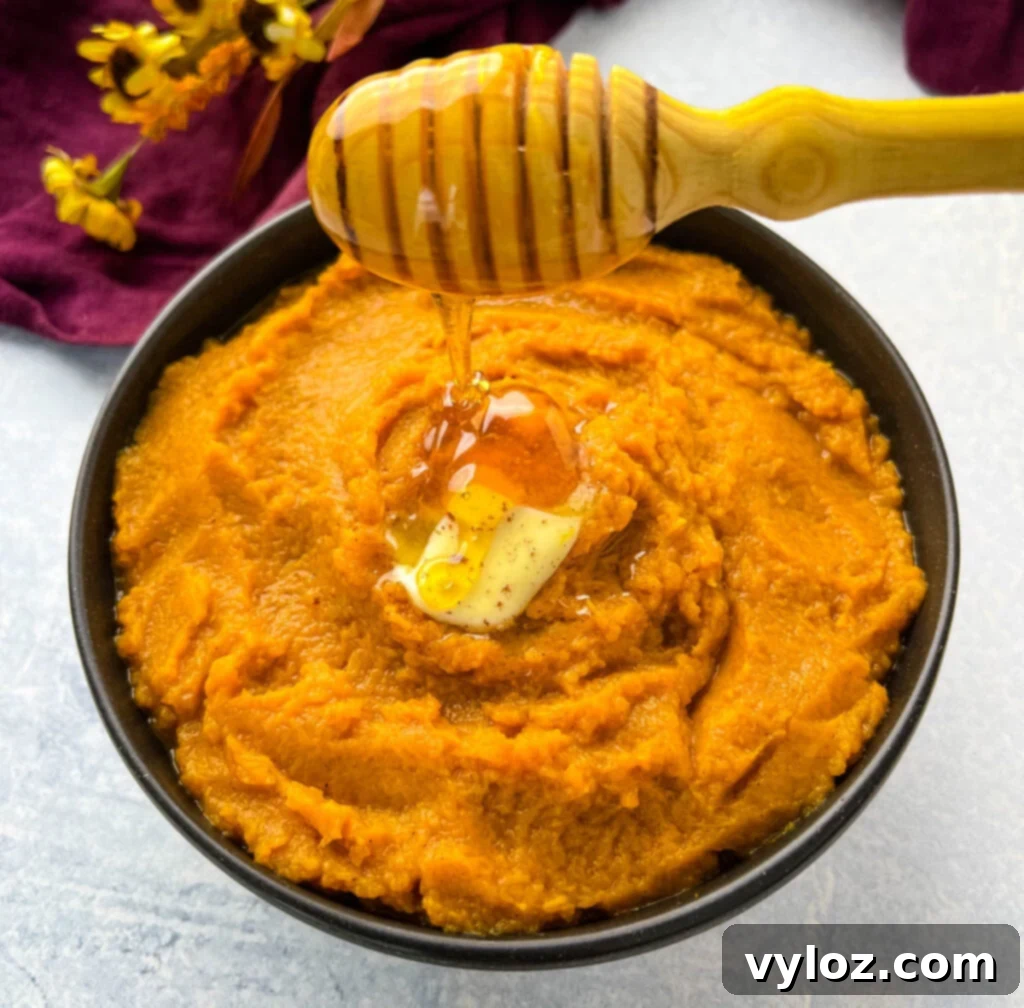 Close-up of mashed sweet potatoes in a bowl, drizzled with melted butter and brown sugar, ready to be served