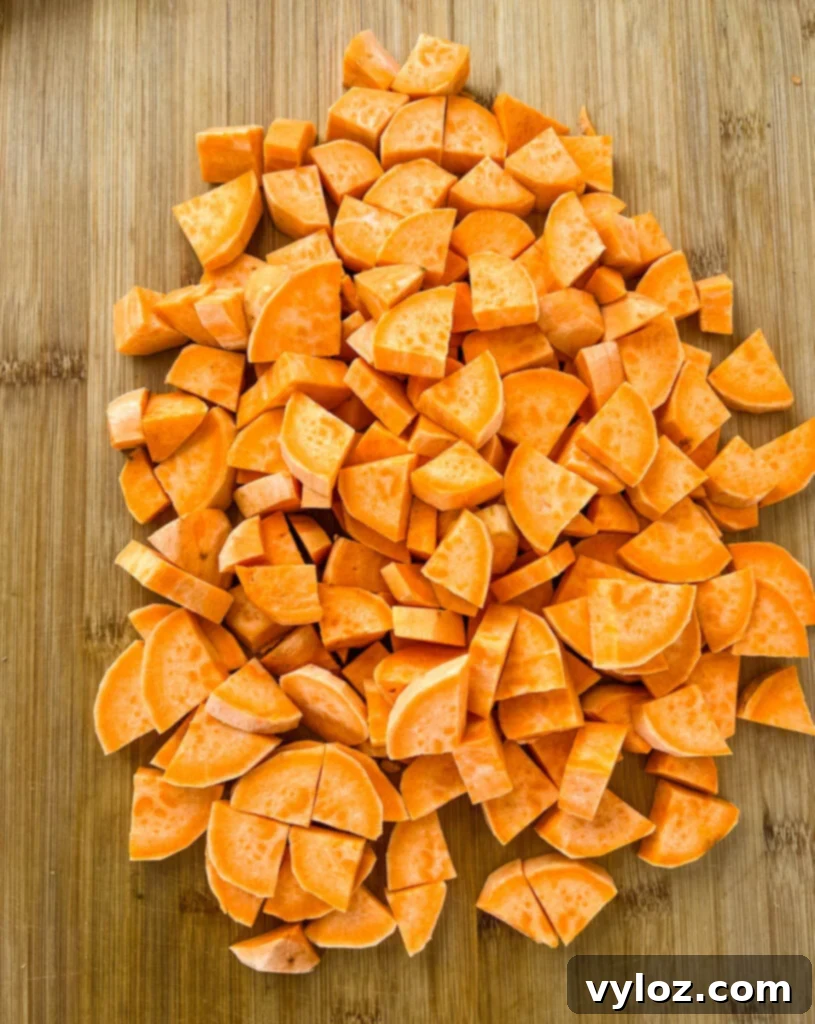 Sliced and cut sweet potatoes on a wooden cutting board, ready for cooking