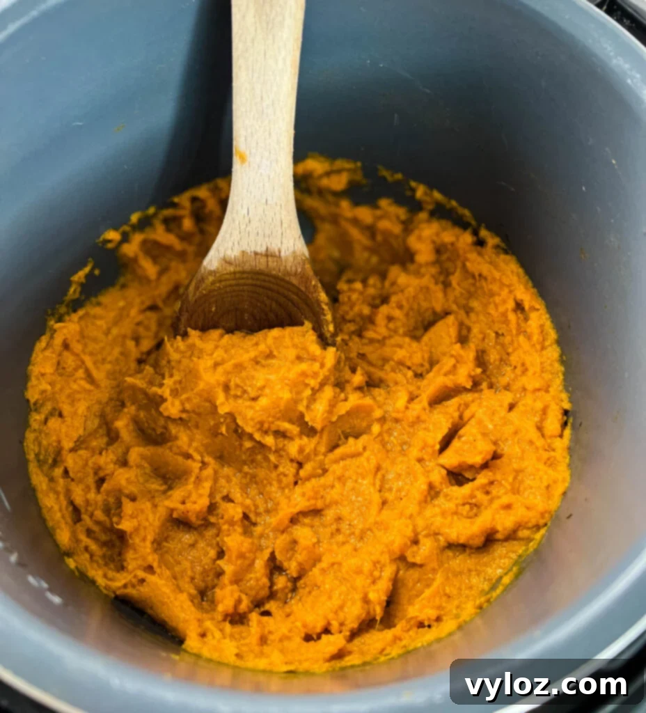 Mashed sweet potatoes in a pot with a wooden spoon, illustrating the creamy texture