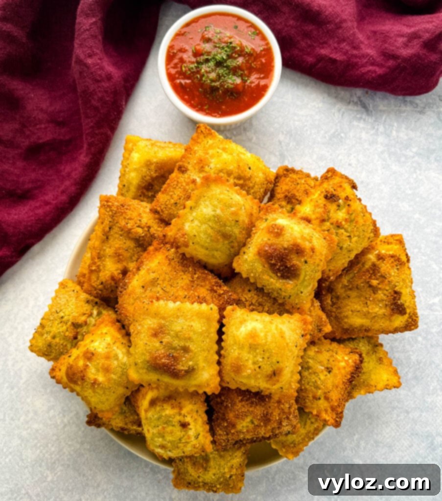 Golden brown air fryer toasted ravioli served on a plate with marinara dipping sauce