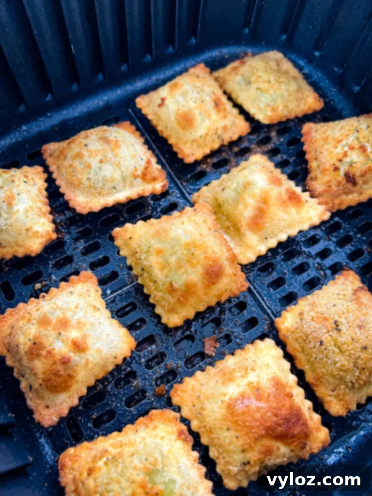 Close-up of golden brown toasted fried ravioli in an air fryer basket, ready to be served