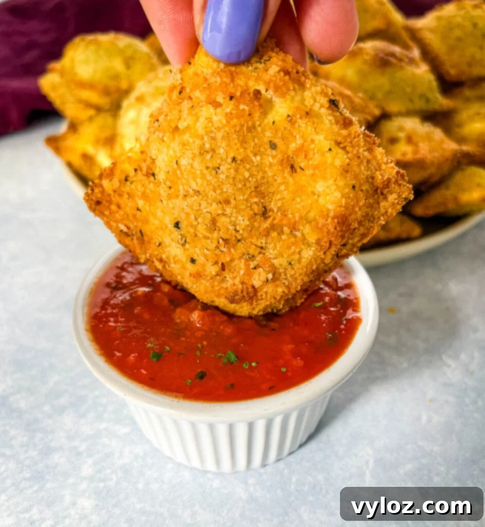 Person holding a plate of air fryer toasted fried ravioli with a side of marinara sauce