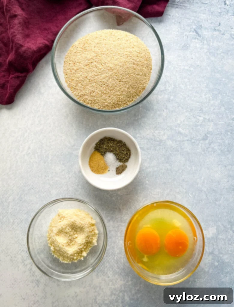 Separate bowls containing breadcrumbs, various spices, grated Parmesan cheese, and raw beaten eggs, ready for breading