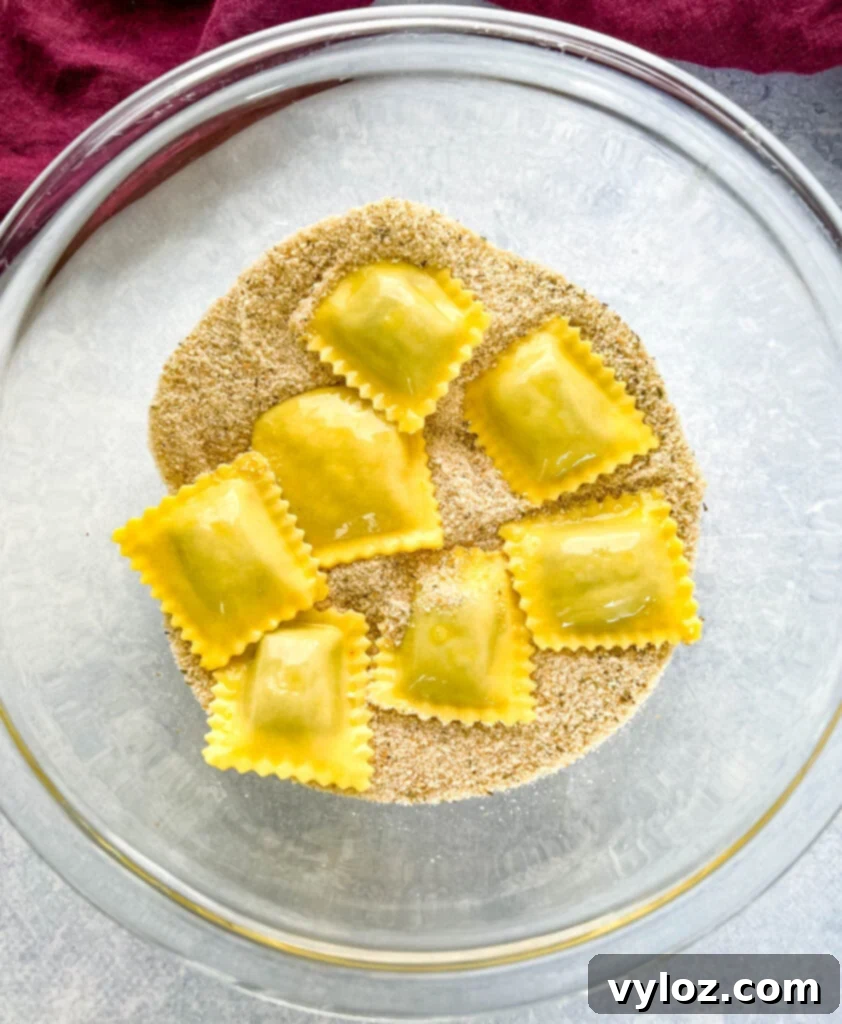 Uncooked ravioli evenly coated in breadcrumbs and egg wash, ready for the air fryer