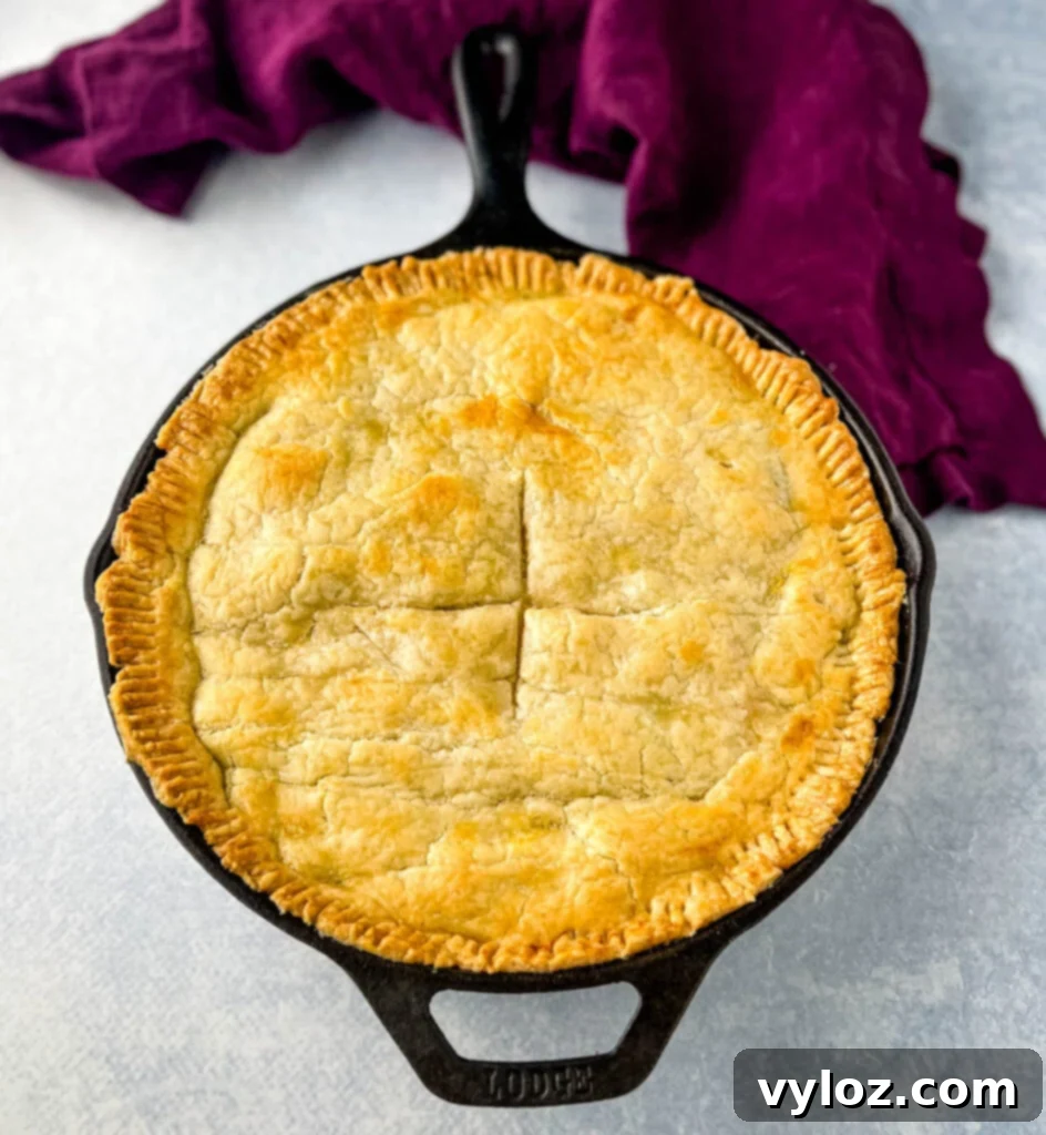 A whole seafood pot pie in a cast iron skillet, ready to be sliced and served.