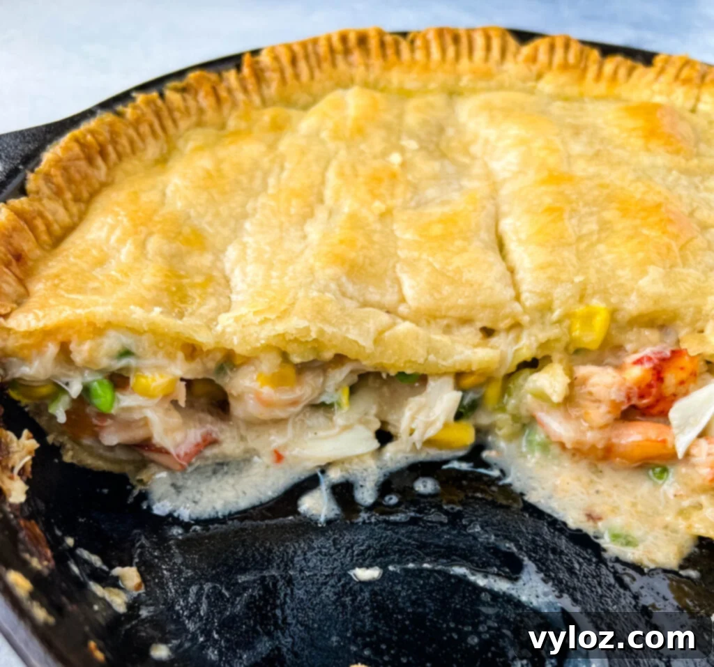 A close-up shot of a baked seafood pot pie in a cast iron skillet, showcasing its golden crust.