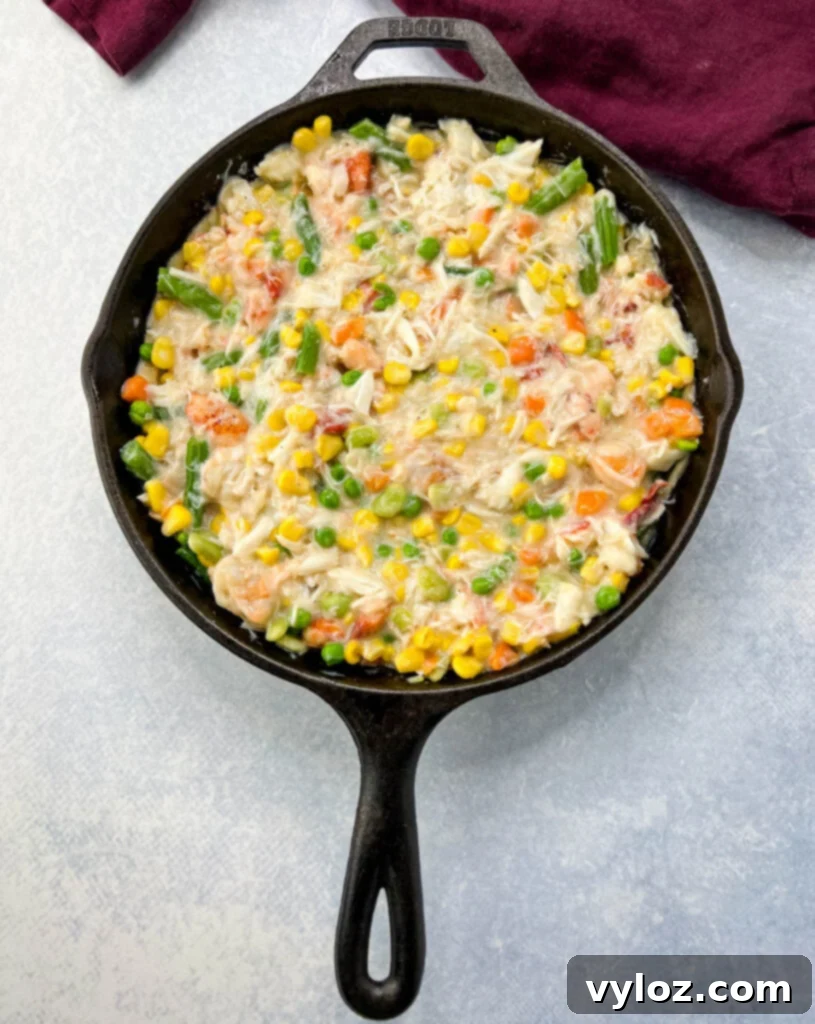 Unbaked seafood pot pie, with top crust and vents, ready for the oven in a cast iron skillet.