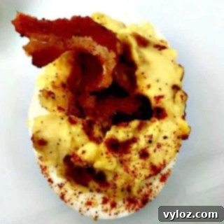 close up of bacon deviled egg on a white plate