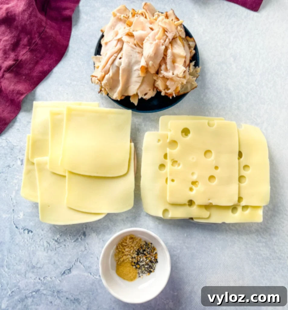 Cheesy Turkey Sliders 3 Various ingredients for turkey sliders: sliced turkey, mozzarella cheese, Swiss cheese, and spices on separate plates