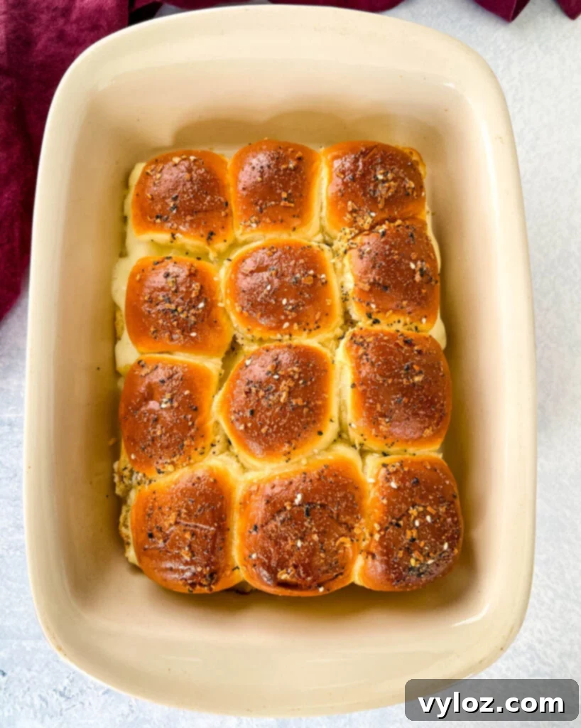 Cheesy Turkey Sliders 8 Oven-baked turkey cheese sliders resting in a baking dish, with melted cheese oozing out slightly