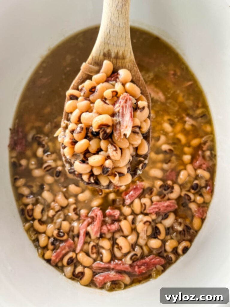No-Soak Slow Cooker Smoked Turkey Black Eyed Peas 9 a wooden spoonful of cooked black eyed peas in slow cooker Crockpot