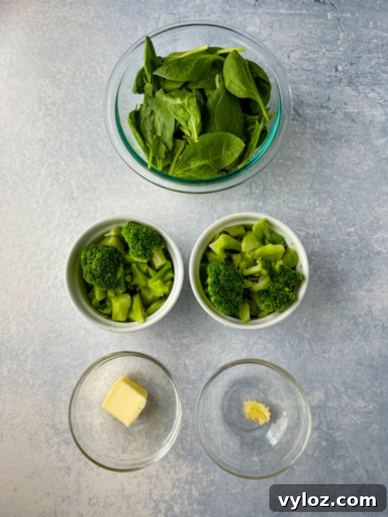 Fresh spinach, steamed broccoli florets, a knob of butter, and minced garlic in separate bowls, ready to be added to the pasta dish.