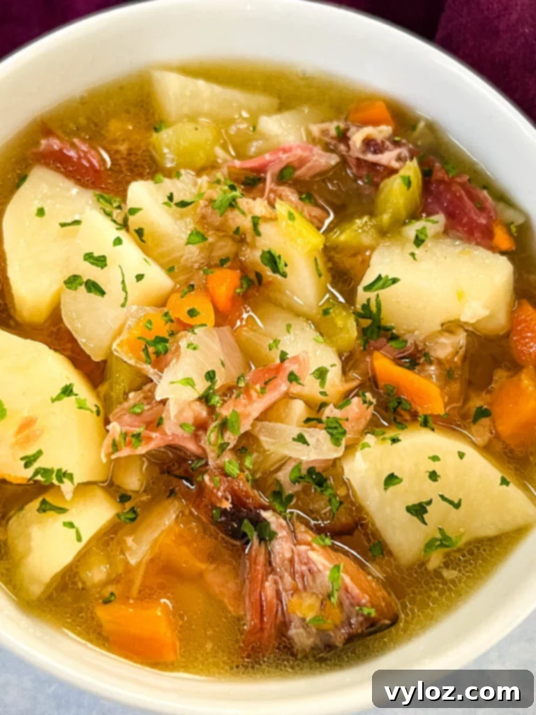 Hearty Slow Cooker Ham, Potato and Vegetable Soup 11 A serving of slow cooker ham and potato soup in a white bowl, ready to be enjoyed.
