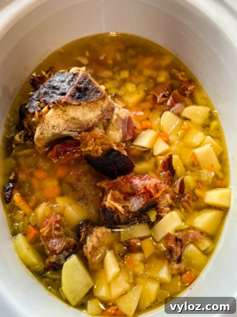 Hearty Slow Cooker Ham, Potato and Vegetable Soup 6 Slow cooker ham and potato soup simmering gently in a Crockpot, with tender vegetables and ham visible.