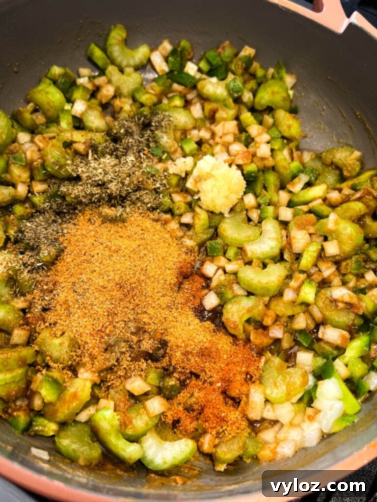 A deep brown gumbo roux combined with diced onions, green peppers, and celery, sautéing in a skillet, representing the Holy Trinity.