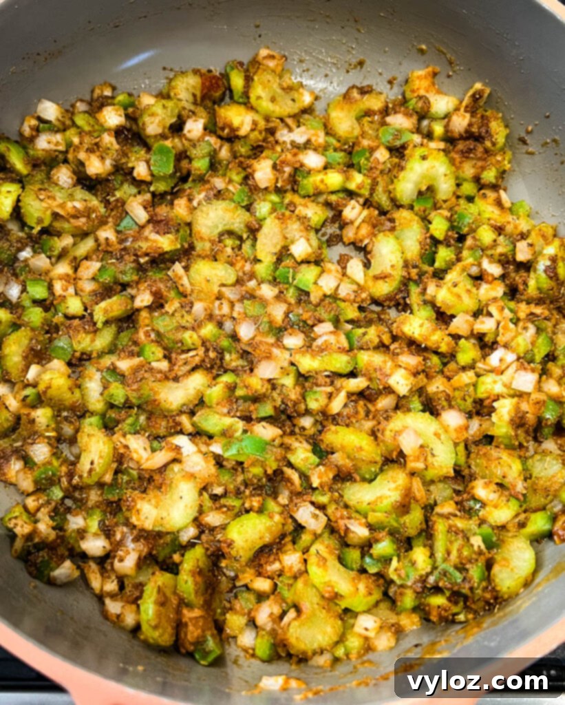 Cooked gumbo roux and the Holy Trinity vegetables simmering together in a skillet, showcasing the rich color development.